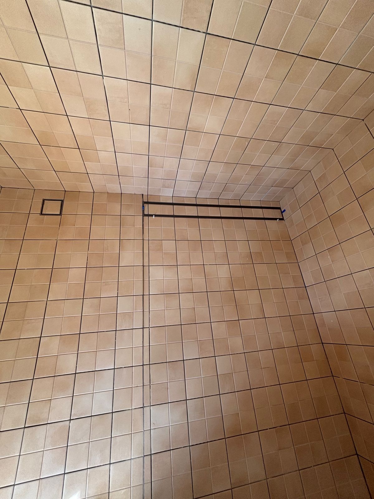 An old bathroom with orange square floor and wall tiles before demolition
