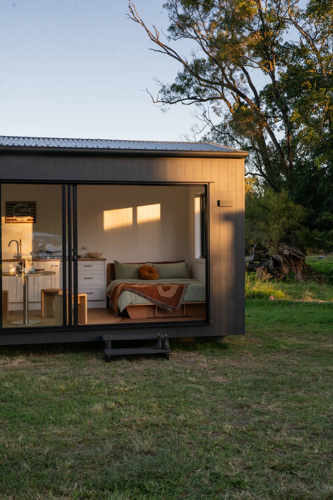 A dark-clad second home at dusk with the doors open and the lights on